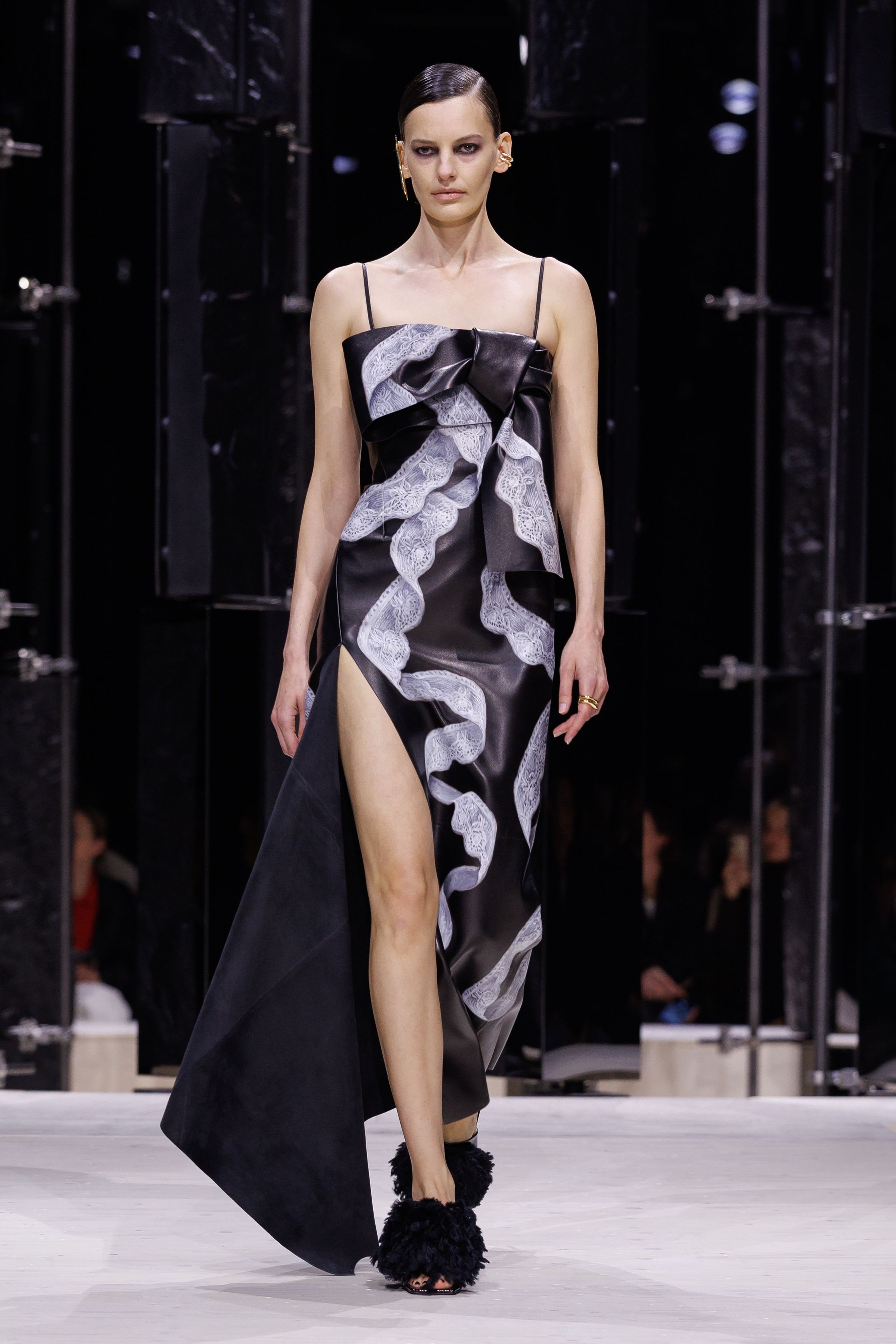 Givenchy 2026秋冬在现代建筑空间中呈现一场充满戏剧性的时装叙事：雕塑式西装、亮色斗篷、结构礼服与夸张装饰共同构建品牌标志性的高级时装气质。蓝色、红色与黄色的高饱和色彩与黑白经典形成鲜明对比，服装通过立体剪裁与夸张廓形展现出强烈视觉张力。整场系列在优雅与戏剧之间取得平衡，展现现代高级时装的力量-顽石频道趋势研究